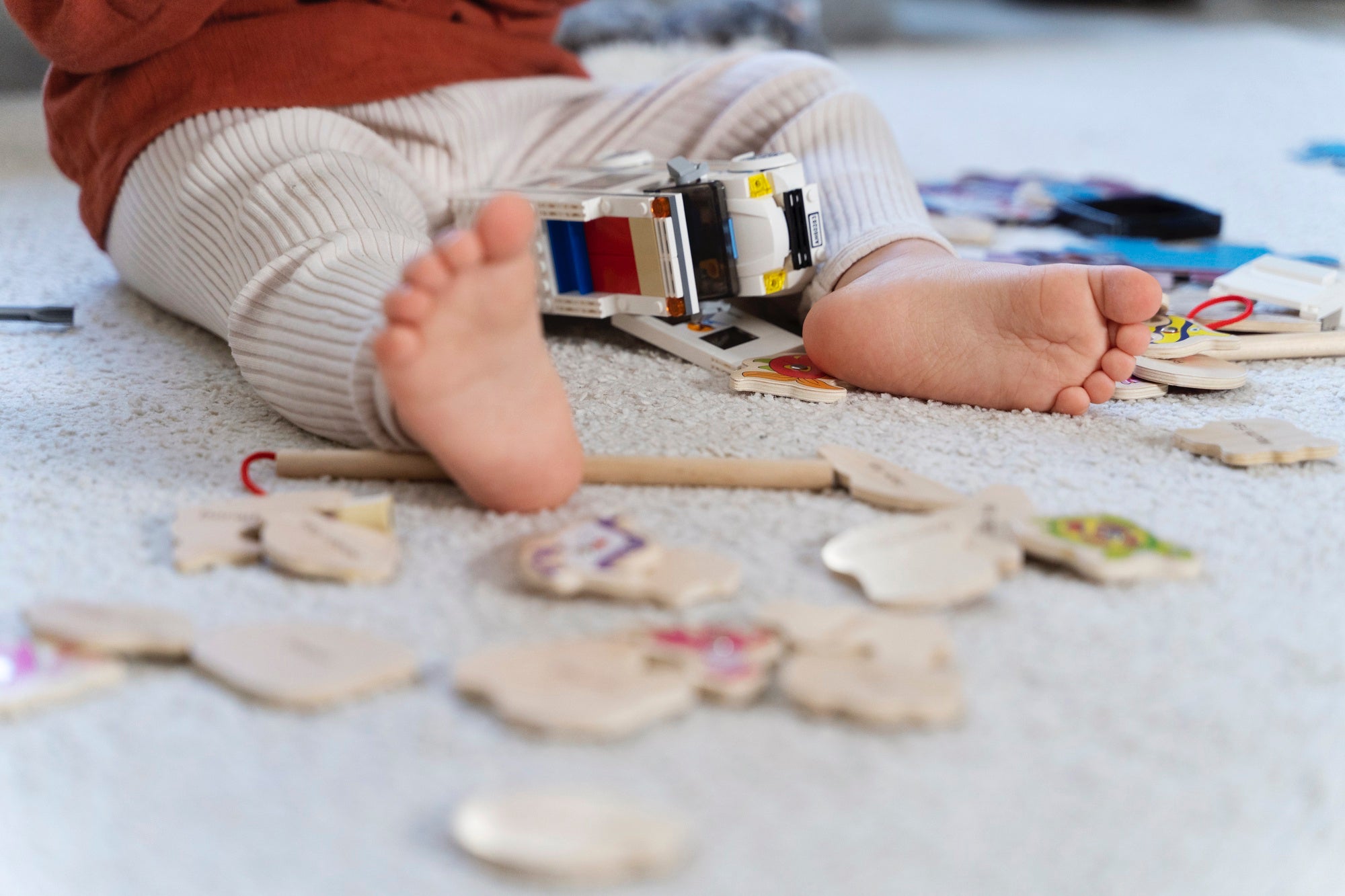 Child's feet with a toy piano and wooden toys on a carpeted floor
